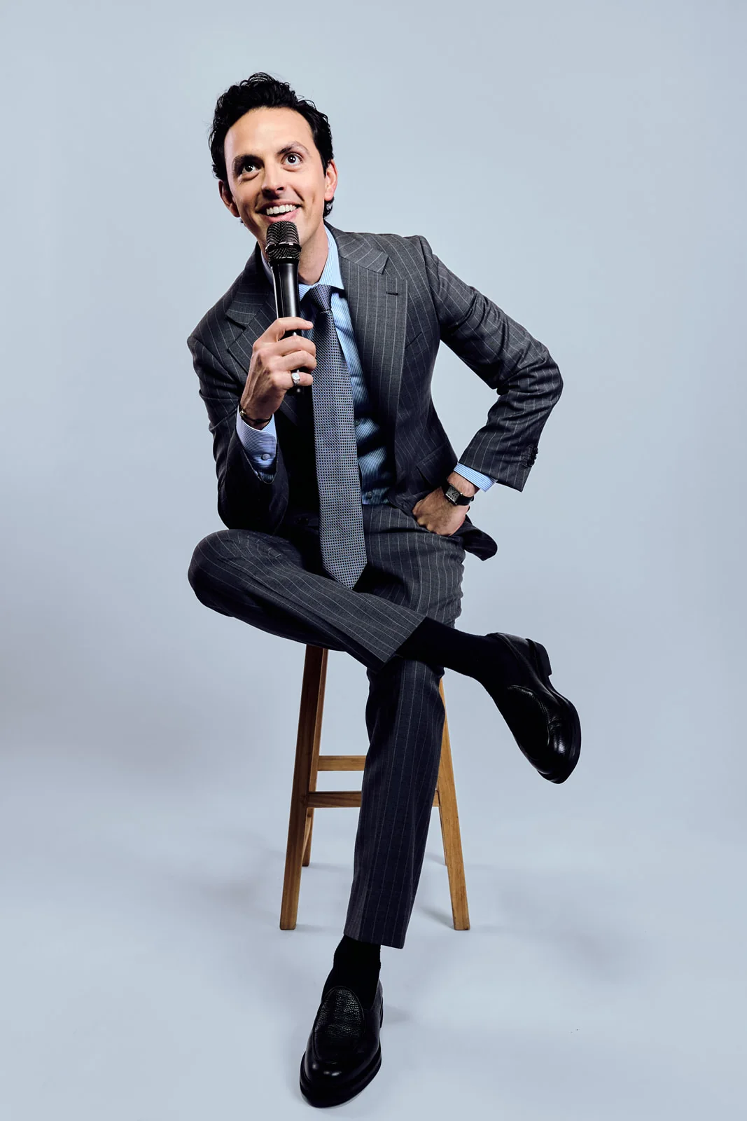 José Ramones sentado con traje y micrófono en retrato editorial