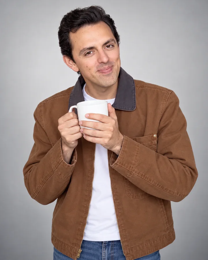 José Ramones como el amigo fan del café, con chaqueta café y una taza blanca