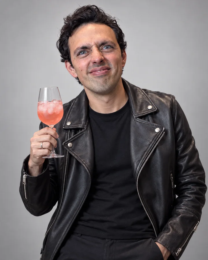 José Ramones como el amigo fresa, con chamarra negra de piel y una copa