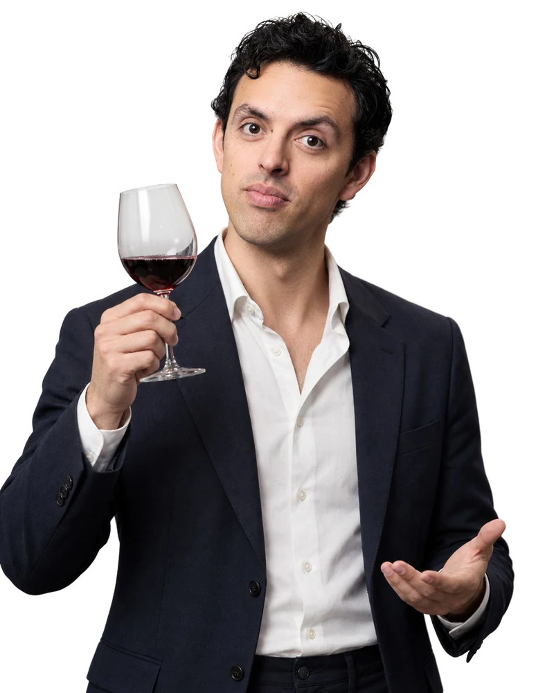José Ramones como el amigo que sabe de vinos, con saco oscuro y copa en la mano