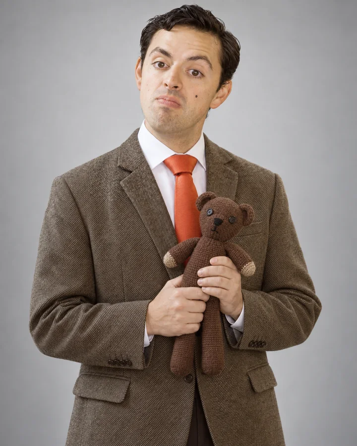 José Ramones como el Señor Frijol, con saco café, corbata roja y un oso de peluche