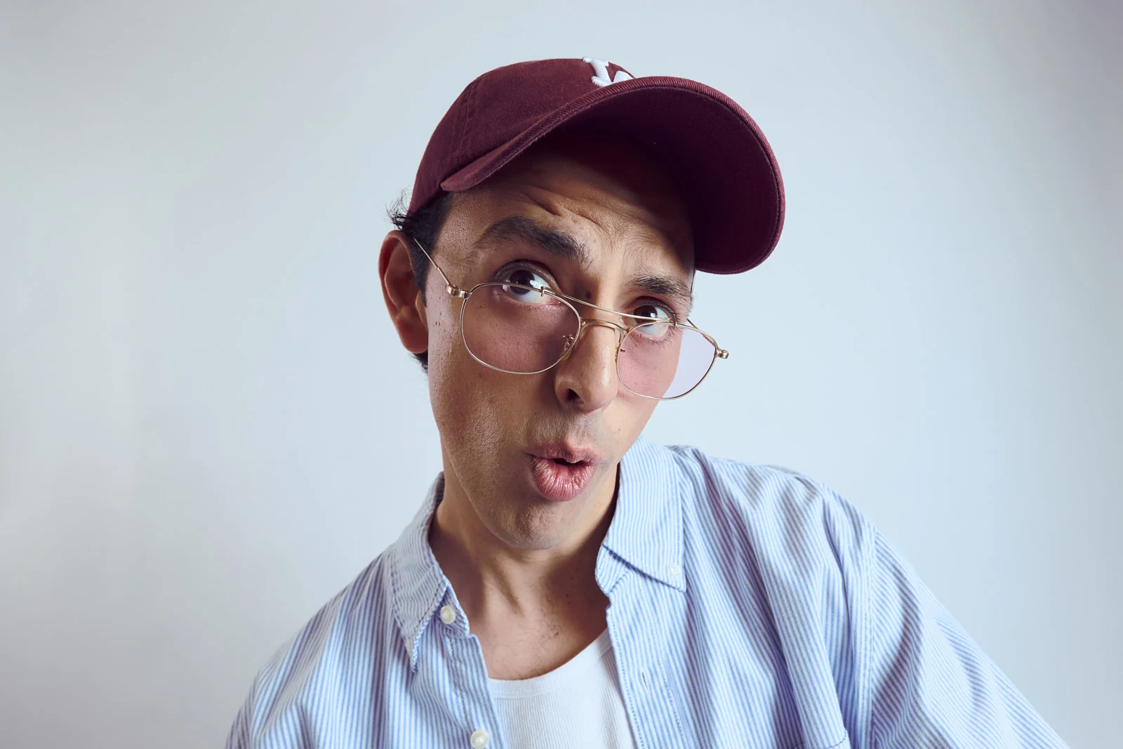 José Ramones con gorra y lentes en un registro de personaje de comedia