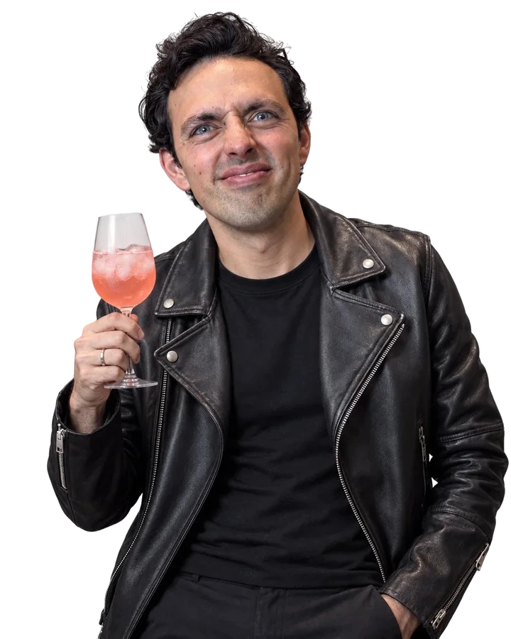 José Ramones como el amigo fresa, con chamarra negra de piel y una copa